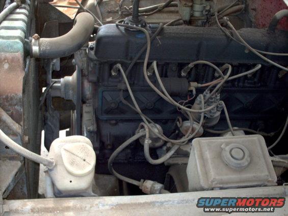 Engine bay with radiator, hoses, and engine block visible. Includes a white plastic fluid reservoir