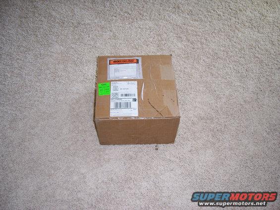 Cardboard box on carpet with shipping labels and 'INVOICE ENCLOSED' sticker