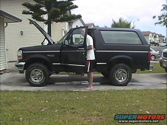 Black 1994 Ford Bronco side view with hood open and door ajar
