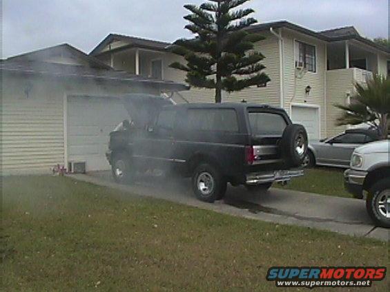 Black 1994 Ford Bronco with hood open and smoke billowing out