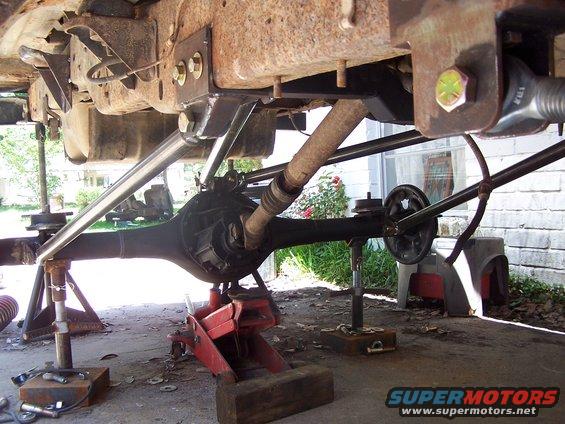 Vehicle underbody showing a modified rear axle and suspension components on jack stands