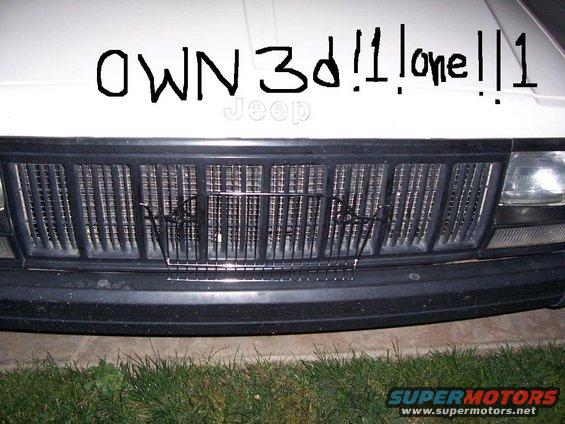 Front grille of a Jeep with "OWN 3d!1 lone!1" written on the hood