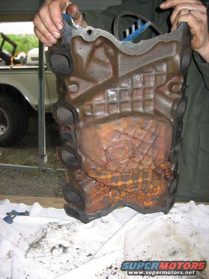 rusted engine cylinder head held by two hands
