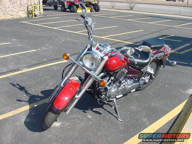 Red motorcycle with chrome accents parked on asphalt, front wheel visible