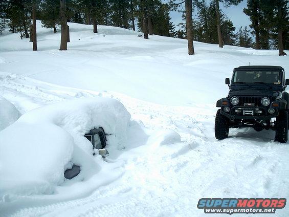 Black Jeep Wrangler parked in snow next to another vehicle buried in snow