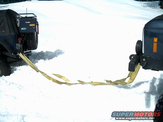Two SUVs connected by a tow strap in a snowy landscape