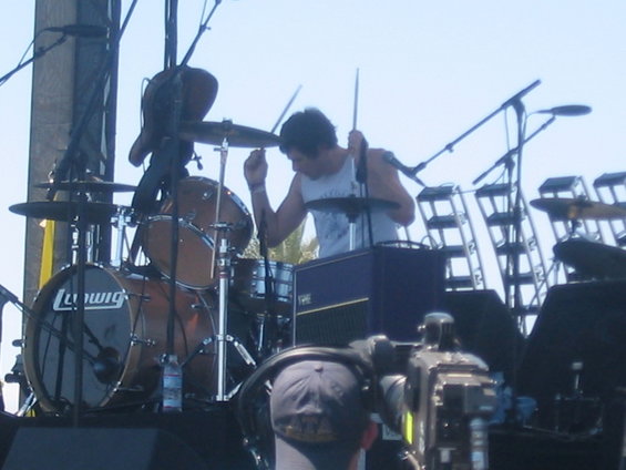 Drummer plays a Ludwig drum kit on an outdoor stage with microphones and lighting rigs