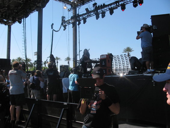 Stage setup with palm trees and a crowd watching a performance