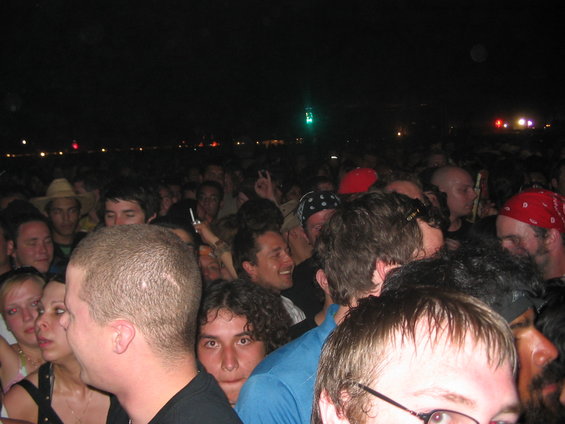 People packed together at an outdoor night event, some with bandanas