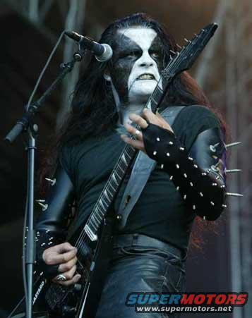 Musician with corpse paint makeup plays guitar on stage
