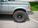 1988 Ford Bronco - A two-tone grey Ford Bronco is shown from the front quarter angle, equipped with large off-road tires.