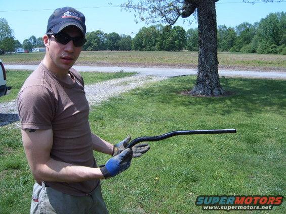 Man holding black flexible tube outdoors