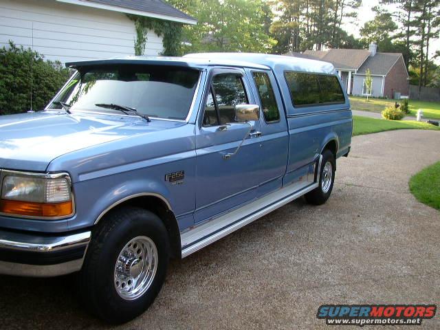 Blue pickup truck with camper shell parked on a driveway