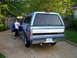 1995 Ford Bronco - Woman holding a baby near the open driver's door of a blue Ford pickup truck with a camper shell.