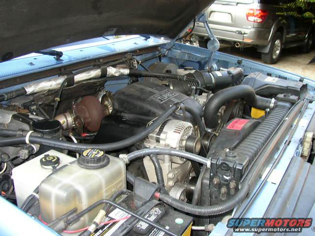 engine bay with turbocharger, other SUV in background