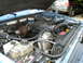 1995 Ford Bronco - The engine bay of a blue vehicle is shown, a turbocharger and other engine components. Another SUV is visible in the background.