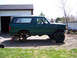 1996 Ford Bronco - Green Ford Bronco undergoing modification with its rear axle removed and lifted on jack stands.