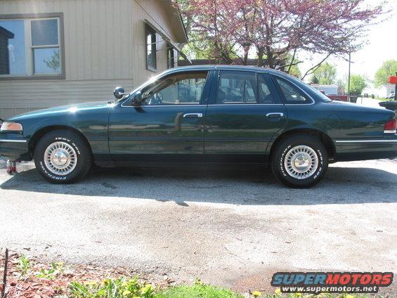 Dark green 1996 Ford Crown Victoria sedan, side view, with chrome trim and wire wheel covers
