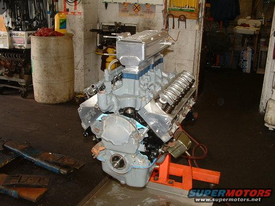 Gray V8 engine on an orange stand, with aluminum valve covers and intake manifold