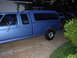 1995 Ford Bronco - This blue pickup truck features a camper shell and appears to be from the early to mid-1990s.
