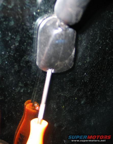 Screwdriver tip inserted into a car's side mirror housing