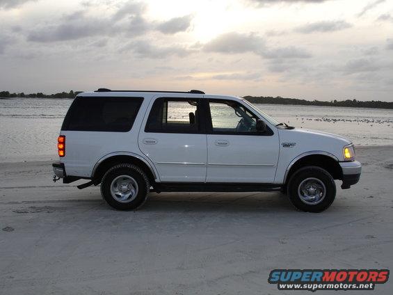 White Ford Expedition parked on a sandy beach near the water