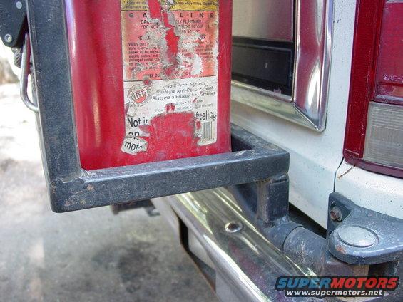 Red jerry can in holder on back of white vehicle, next to taillight