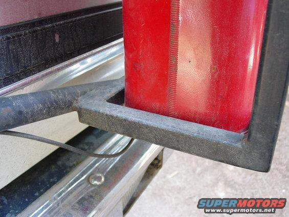 Red jerry can in a metal holder on a vehicle's rear bumper