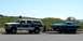 1969 Mercury Cougar - A Ford Bronco is seen towing a classic teal coupe on a trailer under a clear sky.