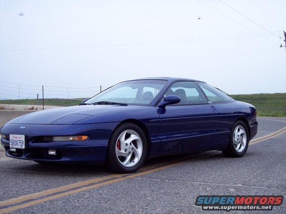 Blue 1995 Ford Probe with aftermarket rims parked on a road