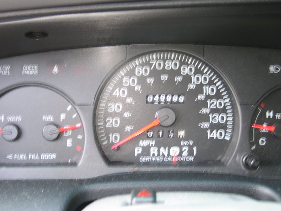 Dashboard gauges with odometer reading 049999, speedometer up to 140 MPH, fuel gauge, and voltmeter