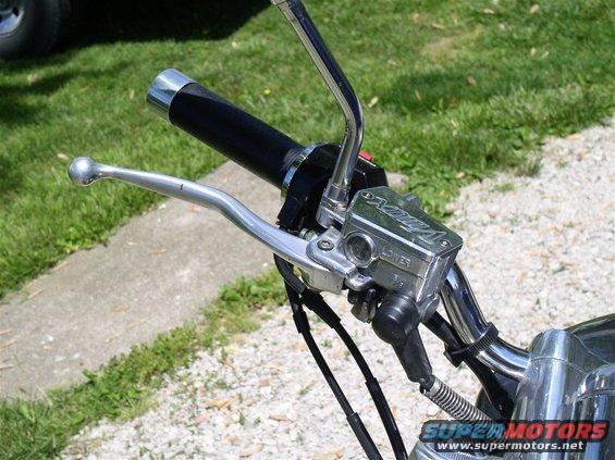 Close-up of motorcycle handlebars with a chrome brake fluid reservoir labeled 'V-Max'