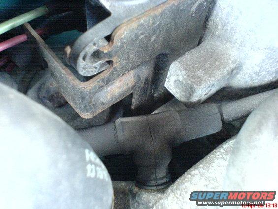 Engine components with hoses and metal brackets. Some rust is visible on the metal parts