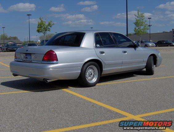 Silver 2002 Ford Crown Victoria, rear 3/4 view, parked in a lot with yellow lines