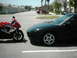 1994 Ford Probe - A red Suzuki motorcycle and a black car are parked side-by-side in a parking lot.