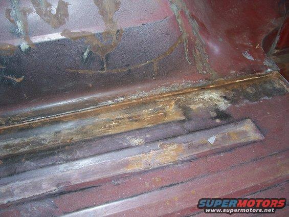 Rusted red metal interior floor with visible seams and support beams