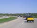 1994 Ford F-250 - A yellow pickup truck tows a trailer with another vehicle on a sunny day on the highway.