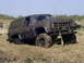 1994 Ford F-250 - Mud-covered GMC SUV stuck in a grassy field with its front grille visible.