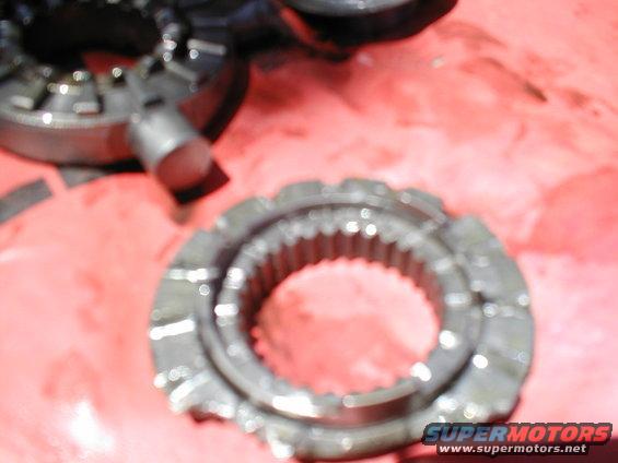 Metal gears on a red surface. One gear is in focus, showing its teeth and inner splines