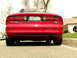 1993 Ford Probe - The rear of a red Ford Probe GT is parked on a residential street, showing its taillights and dual exhaust pipes.