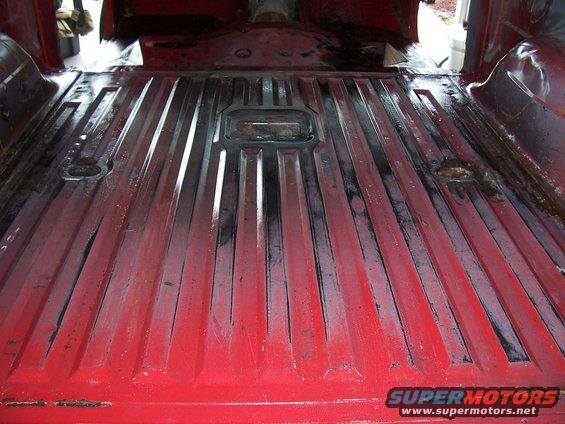 Red truck bed interior with ribbed flooring and tie-down points