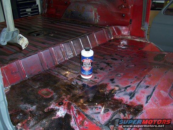 Interior floor pan of a vehicle undergoing restoration, showing rust and a can of Jasco Prep & Primer