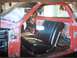 1968 Ford Ranchero - Interior view of a red vehicle with a black bench seat and exposed door panels, suggesting it is in a state of repair.