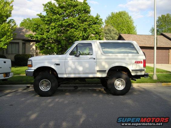 White lifted Ford Bronco with large tires parked on a street