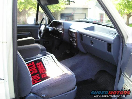 1990 Ford Bronco interior showing dashboard, seats, and a "For Sale By Owner" sign