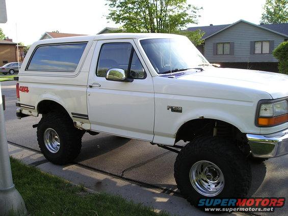 White Ford Bronco with lifted suspension and large tires, viewed from the front three-quarter angle