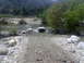 1988 Ford Bronco - A white SUV navigates a shallow, rocky river in a natural landscape.