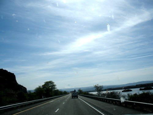 Car driving on a highway with a mountain in the distance and water to the right