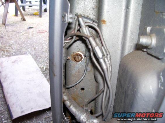 Close-up of vehicle wiring harness and a rusty mounting bracket
