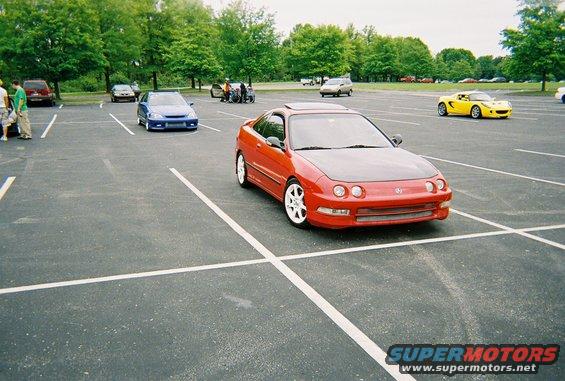 Red coupe with black hood parked in a lot